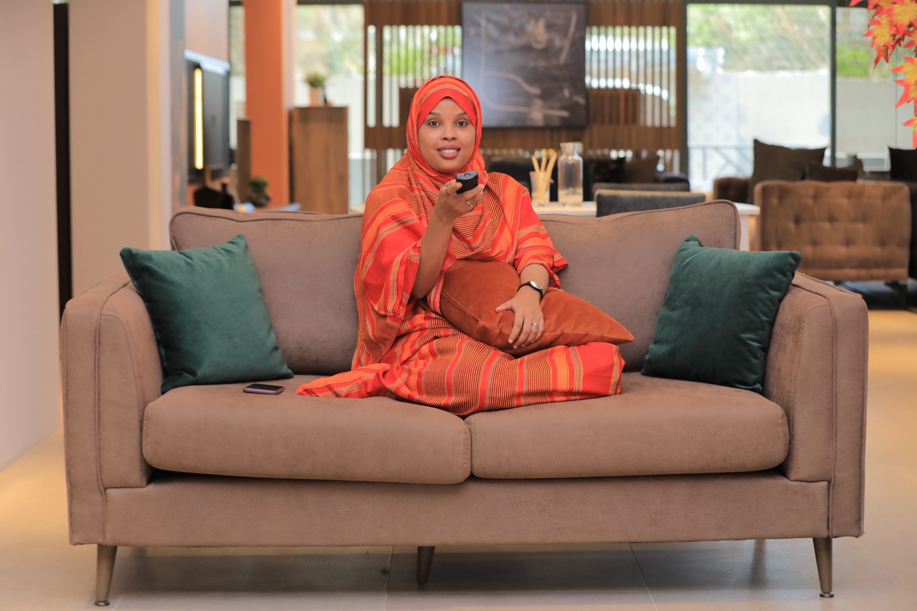 An Astaan presenter reviewing post results on her phone in the studio lounge
